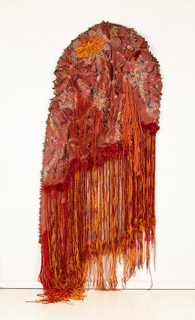 Skin of Unfolding Desires is made of latex rubber, acrylic ink, threads, stone eyes, cowrie shells and brass washer